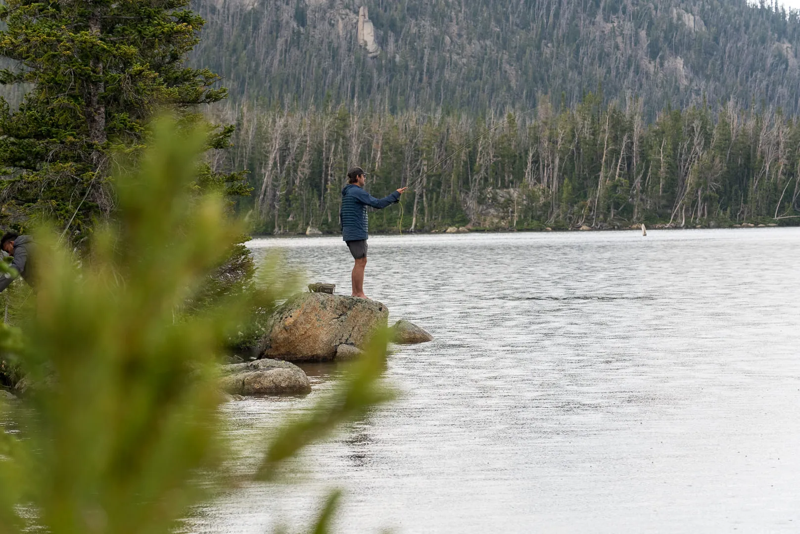 A quiet alpine lake in southwest Montana under flat light, a forested ridge across the water.